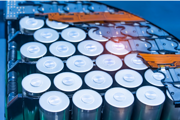 Close-up of silver cylindrical battery cells arranged in a grid inside a battery pack, showing metal cell tops, black holders and orange flexible circuit connectors.