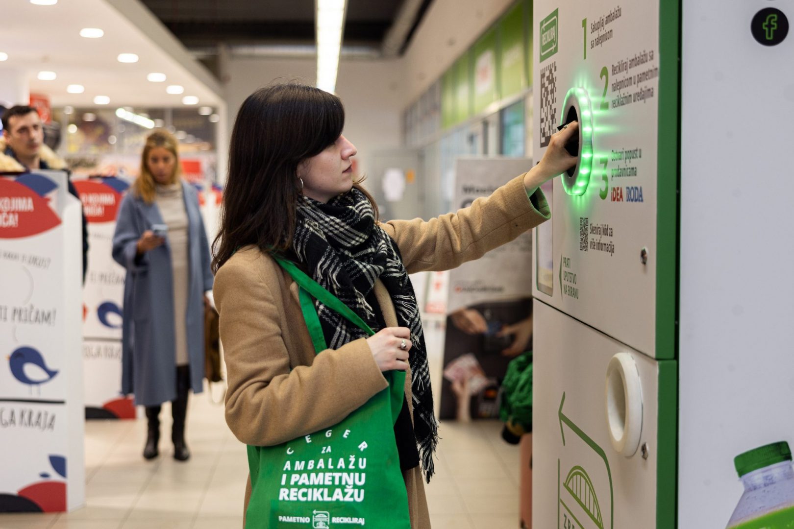 Kobieta używa automatu do recyklingu butelek w centrum handlowym.